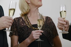 Mature woman standing between two men, each holding drinks, close-up