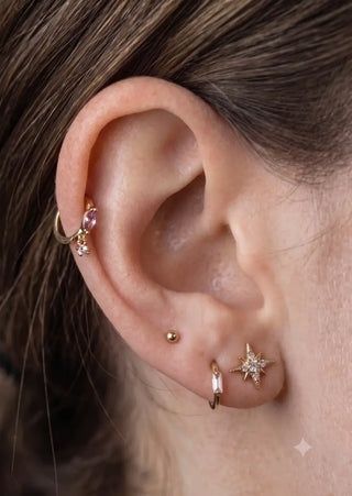 Close-up of an ear with multiple delicate cartilage and lobe piercings