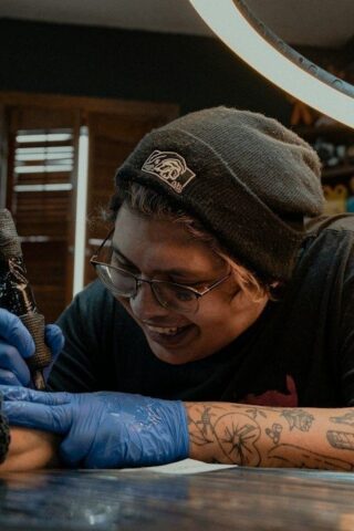 Tattoo artist wearing gloves works on a client's arm