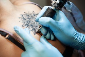 Tattoo artist at work on a girl's backpiece